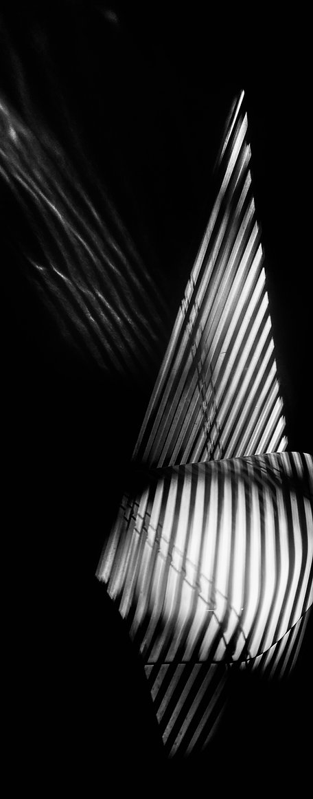 Abstract black and white image of light and shadow creating sharp triangular and striped patterns, high contrast